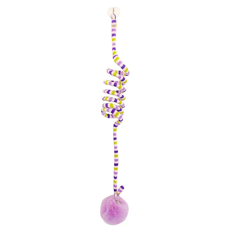 Spring cat toy with coloured inflatable ball and bell hanging from suction cup on glass door
