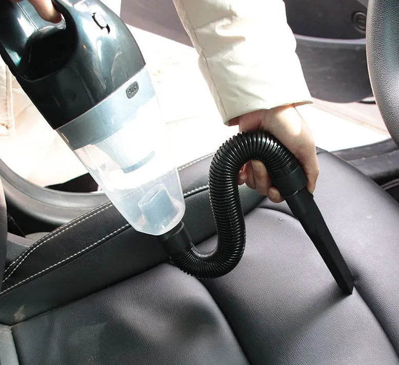Orange handheld 12V car vacuum cleaner with nozzle attachments next to a car interior.
