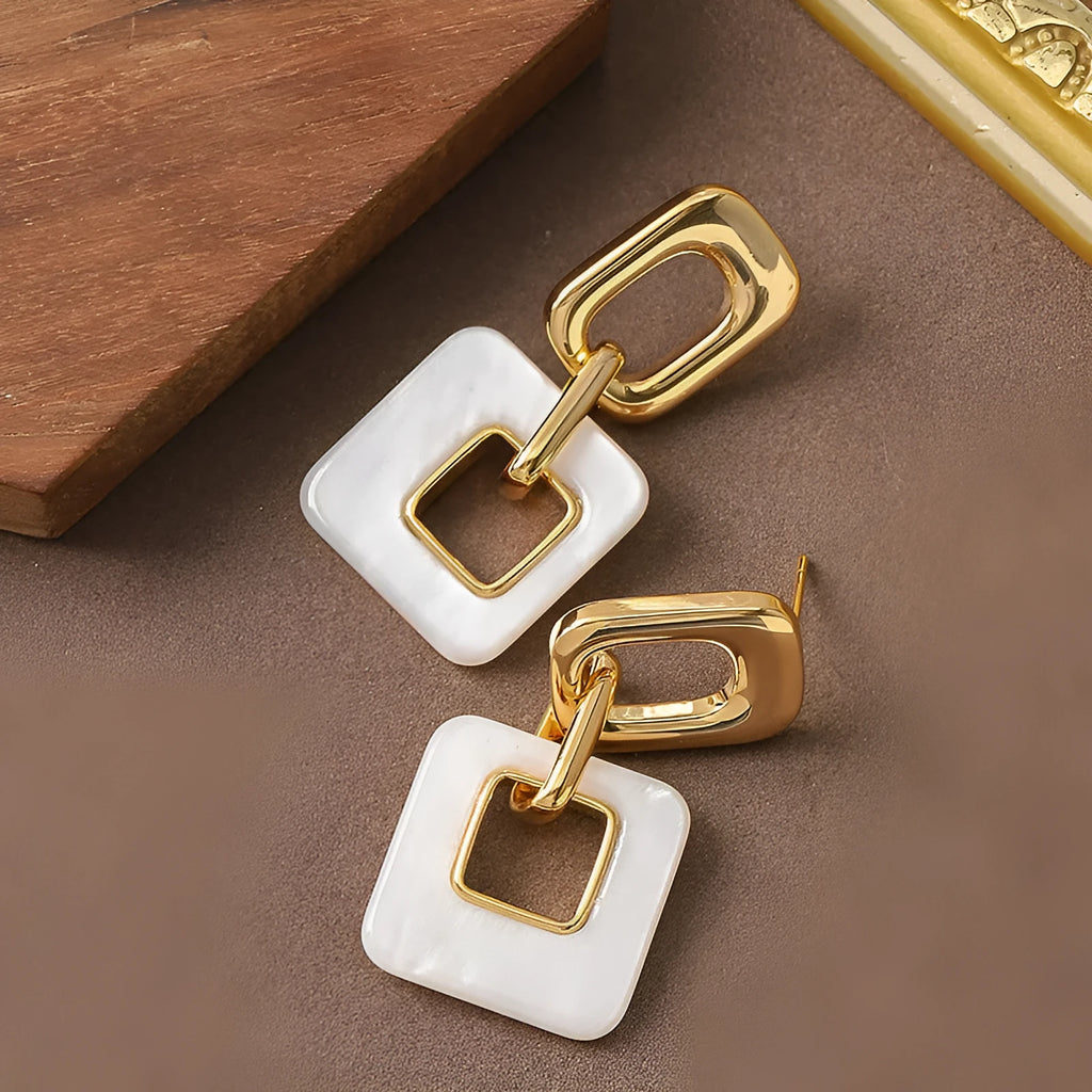 A pair of hollow geometric square earrings with a chamfered pattern, shown in an electroplated finish.
