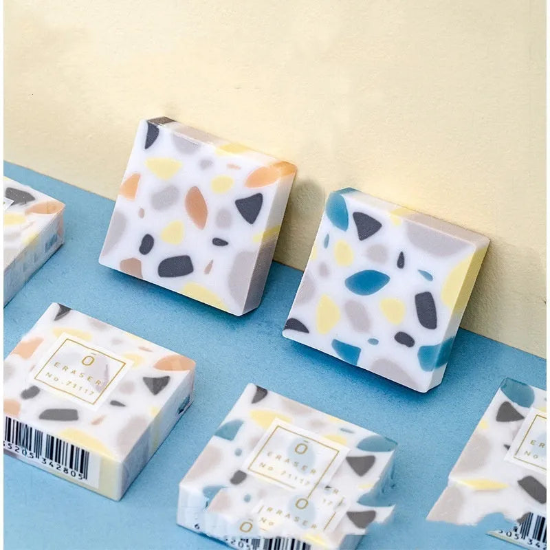 A single white rubber eraser in a brick shape with straight edges, for cleaning pencil marks from paper.
