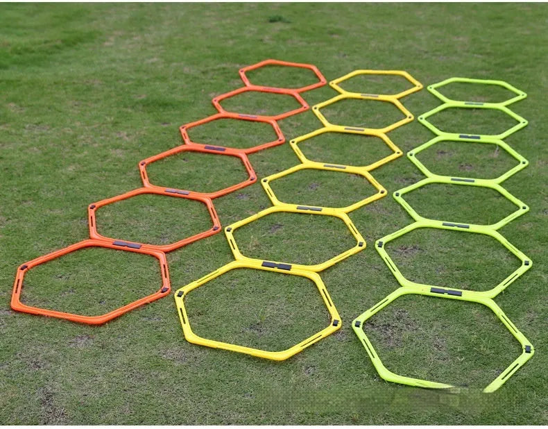 Set of six brightly coloured foldable hexagon football agility training rings on grass