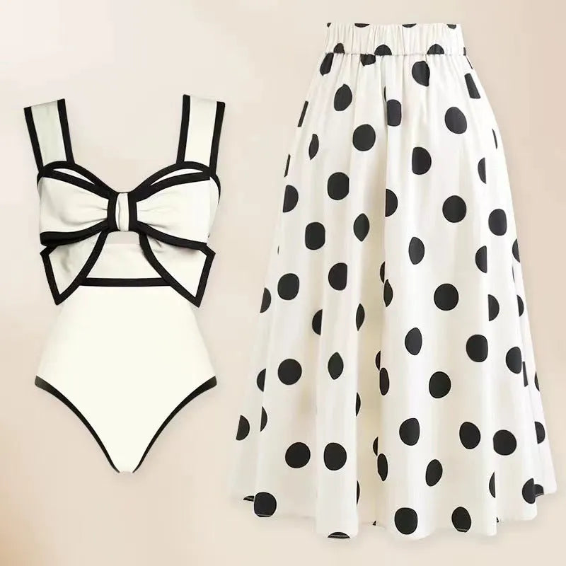 Women's black one-piece swimsuit with a white flared skirt and a central bow detail.
