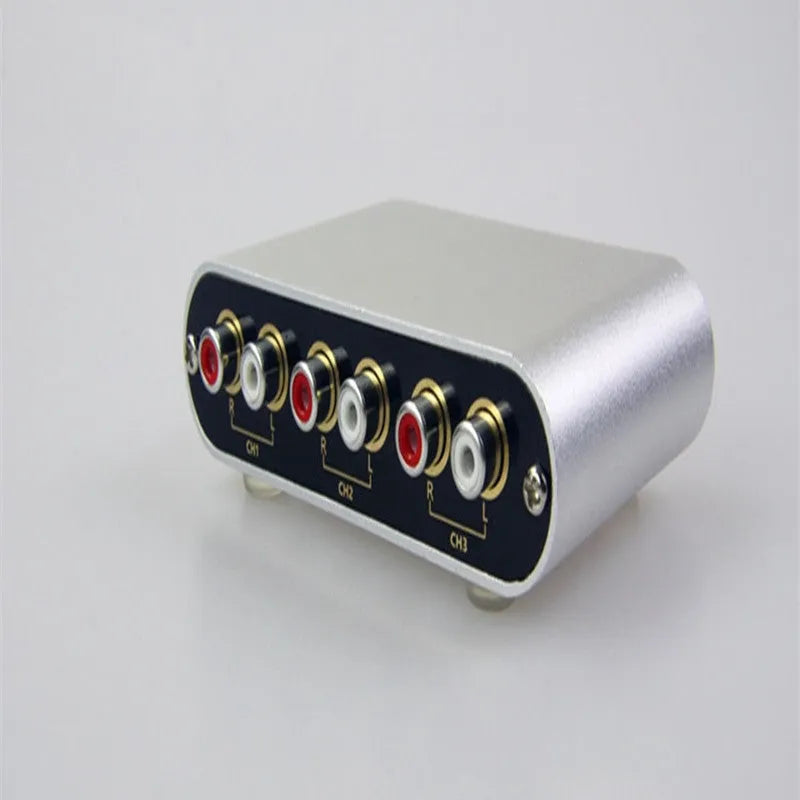 Silver aluminium audio source selector switch unit with front-panel buttons and infrared remote control.