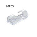 Transparent plastic self-adhesive cable clips for wire management on a desk.