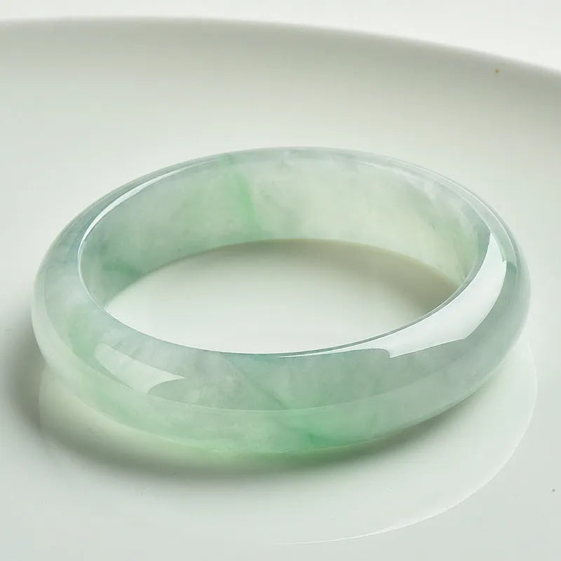 Light green jade bracelet on a white background, showing natural stone texture.