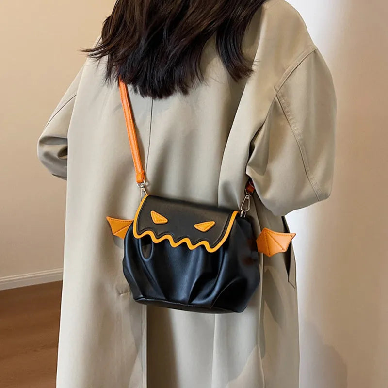 Orange PU crossbody bag with pumpkin cartoon shape and small wings, placed on a neutral background