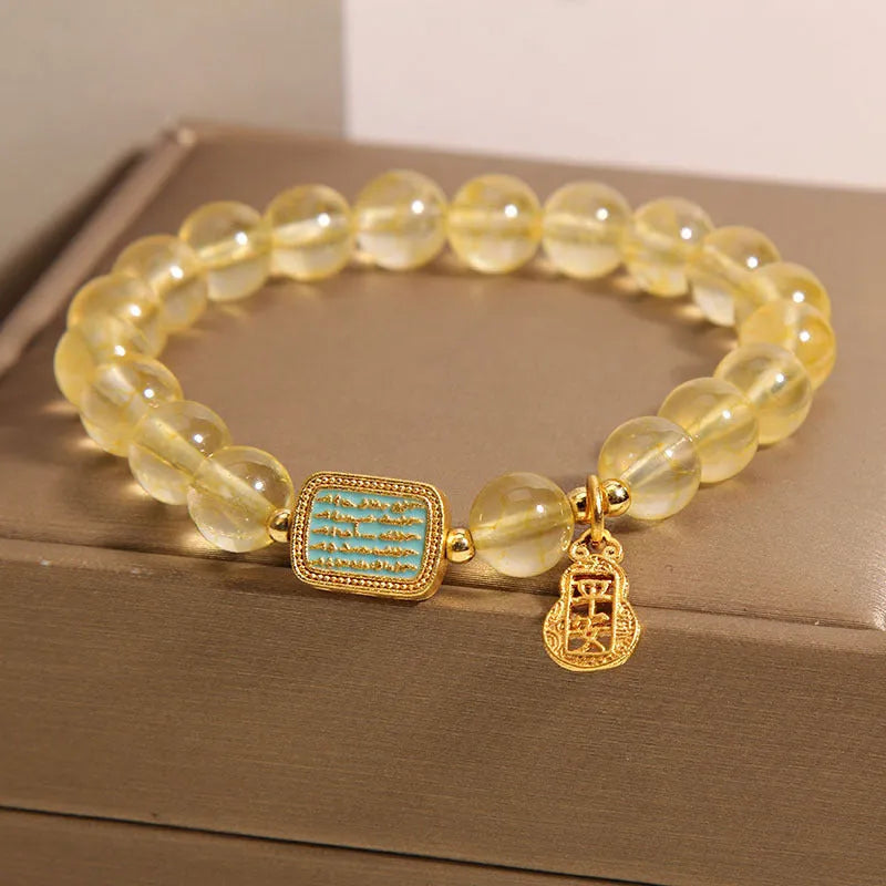 Women's bracelet with yellow citrine stones and sparkling rhinestone details on a white background.