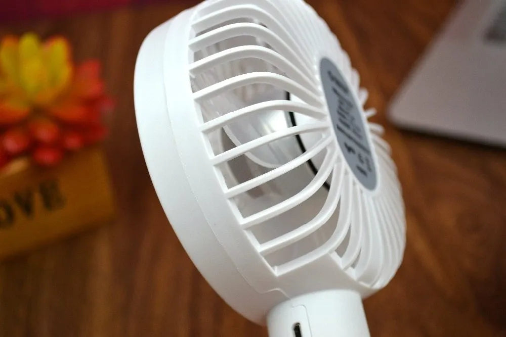 White ORICO FH1 portable USB rechargeable fan with fine line detailing, shown in handheld and desktop positions.