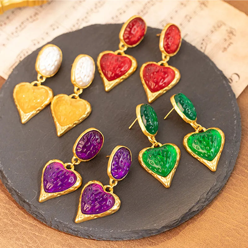 A pair of oval-shaped heart stud earrings with a silver needle texture in purple, red, green, and yellow white colours