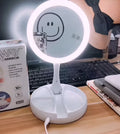 White foldable LED vanity mirror with a ring light, shown open on a table.
