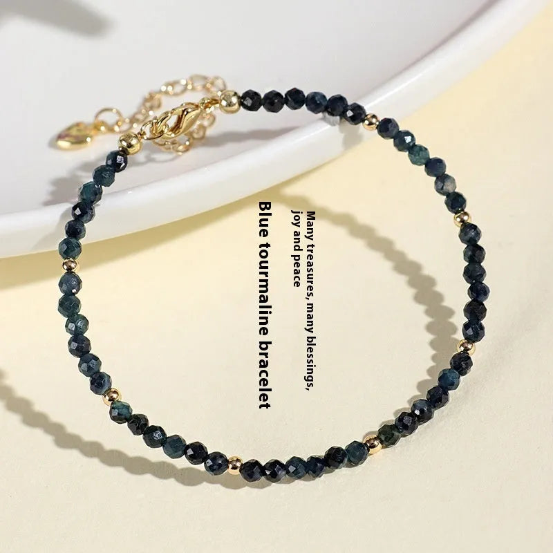 Close-up of a women's bracelet with small blue tourmaline beads and spacer beads on a wrist.