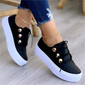 Women's white lace-up flats sneakers with decorative silver rivet details and round toe