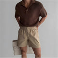 Men's loose-fit cotton sports shorts in khaki colour on a hanger.