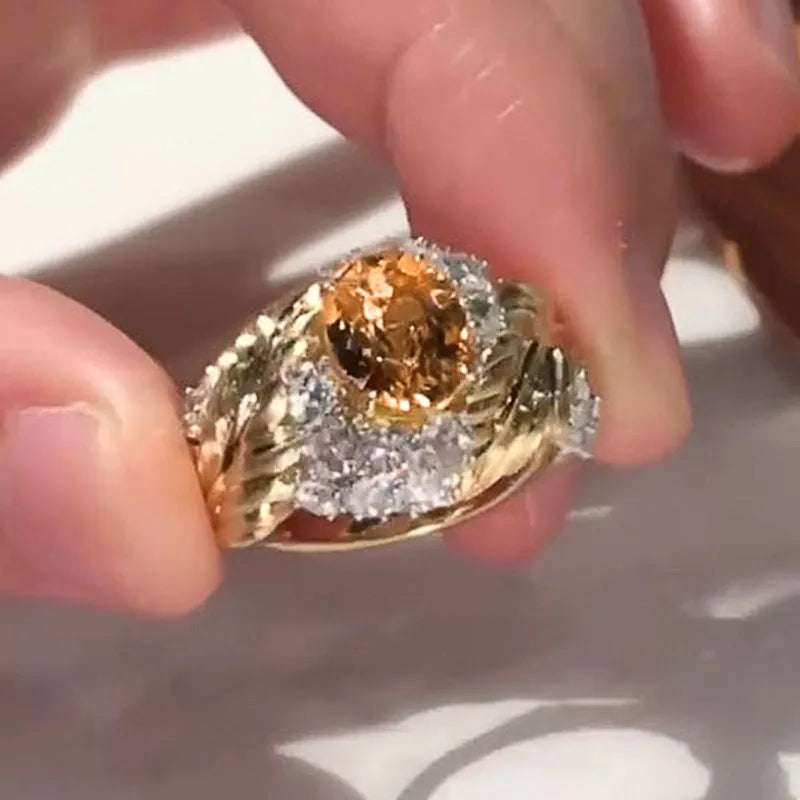 Gold-coloured embossed feather fashion ring with geometric shape and inlaid yellow zircon stones.