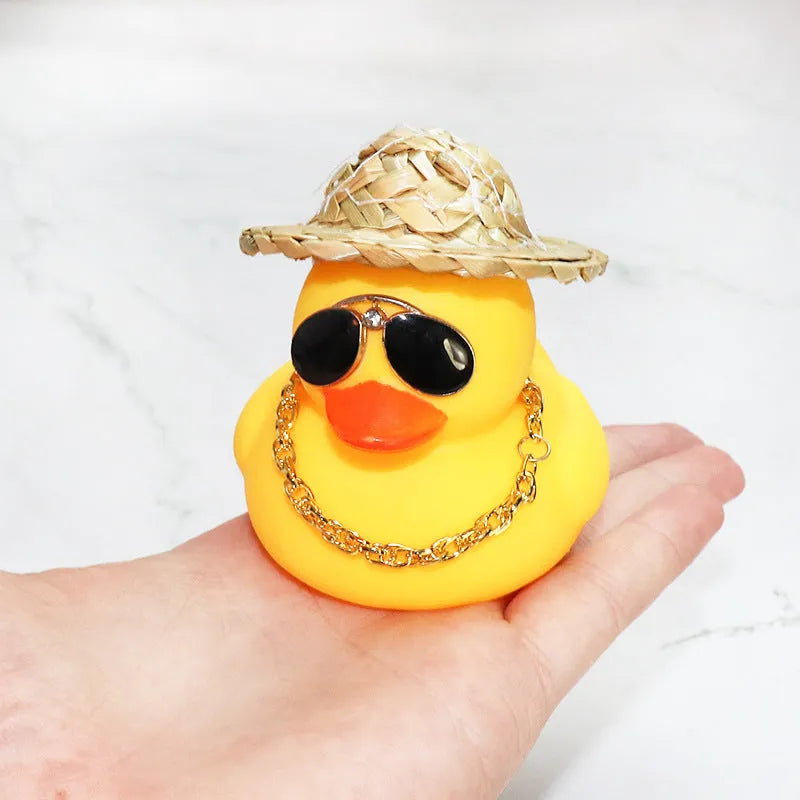 Matte yellow cartoon duck wearing a straw hat car ornament on a dashboard.
