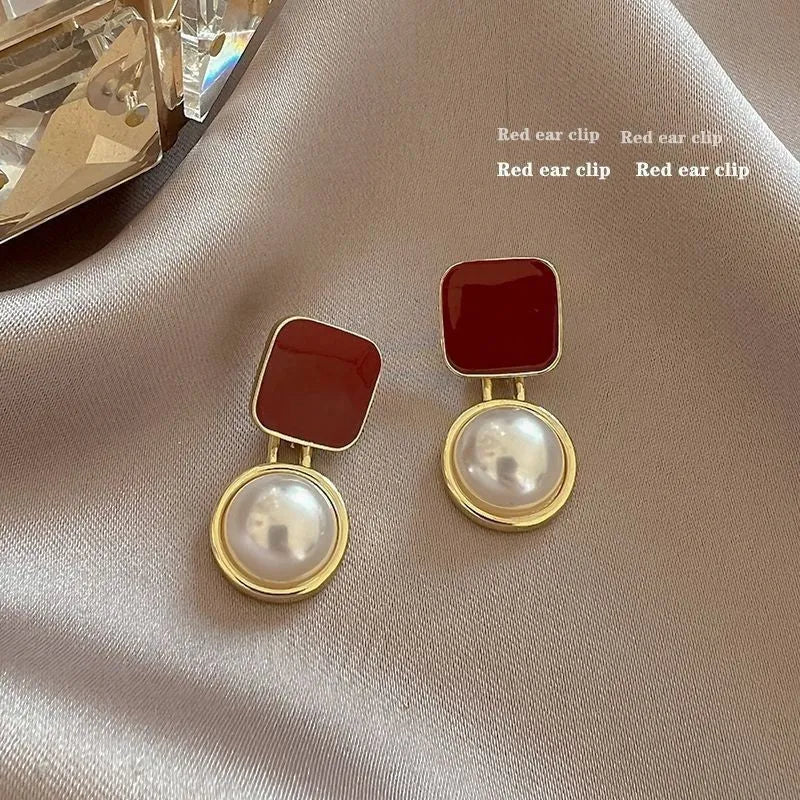 Red geometric alloy stud earrings with pearl centre on white background