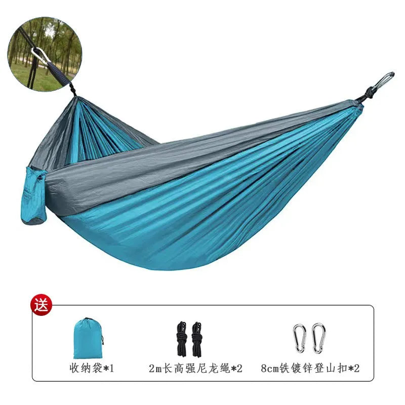 Blue outdoor camping hammock hanging between trees with ropes and carabiners