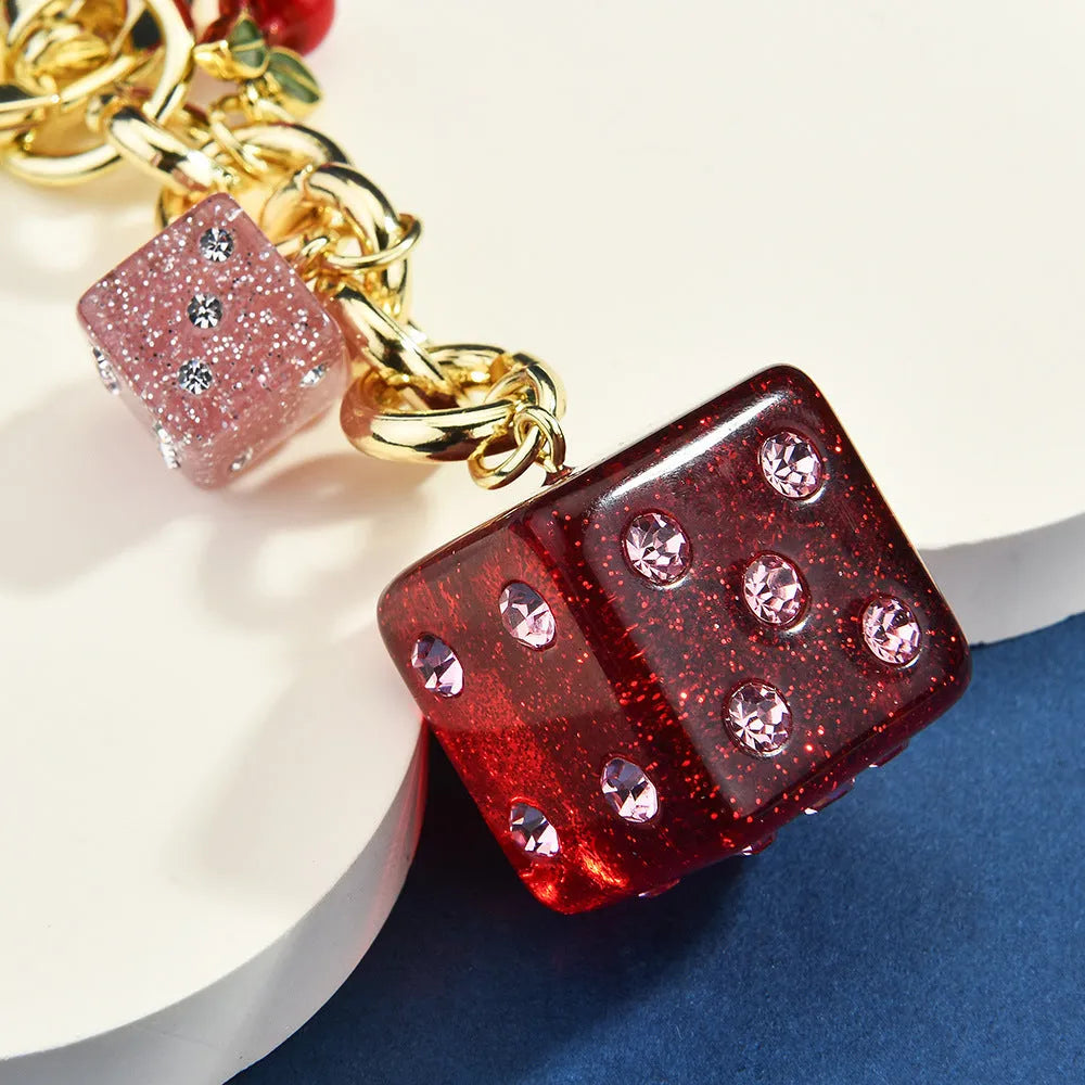 Close-up of a square metal keychain pendant with a two-tone red cherry dice pattern.