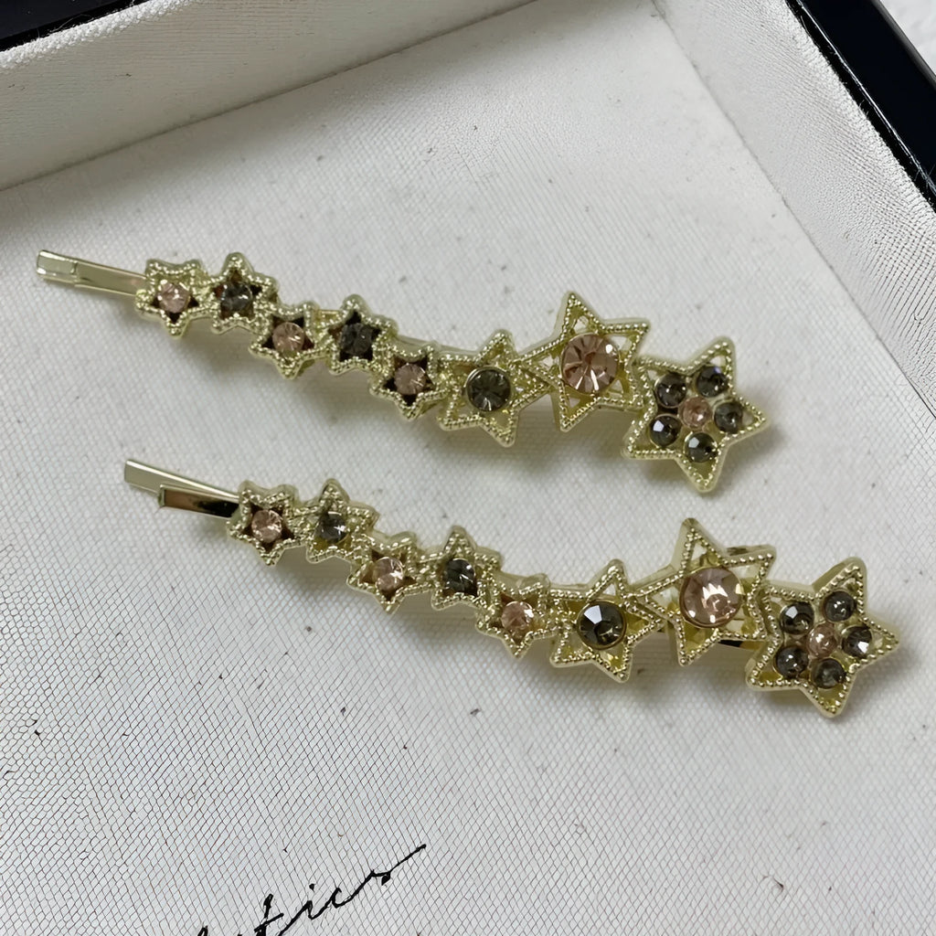 Gold-coloured alloy hair barrette with a side clip, rhinestones, a star, and a word decoration.