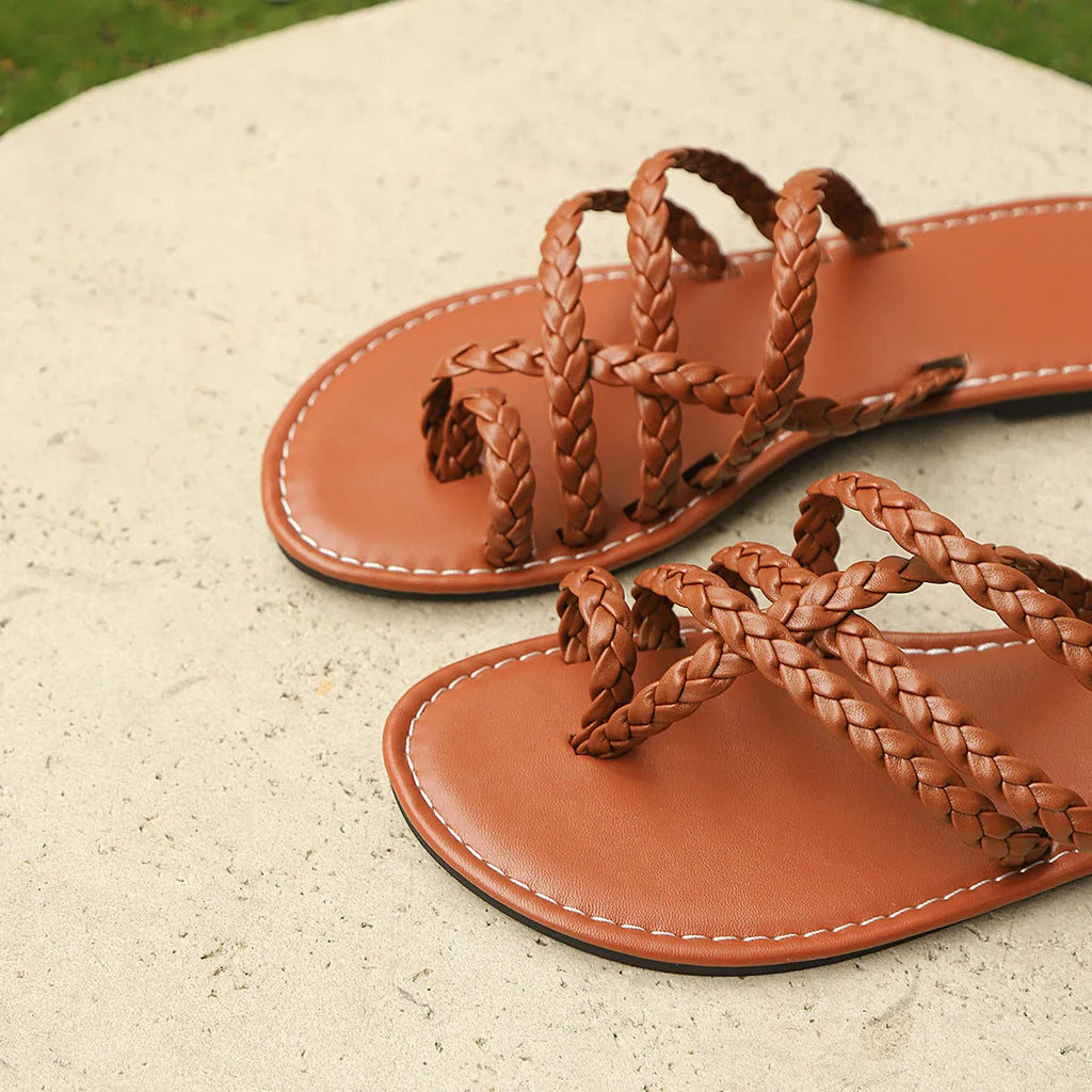 Women's white woven clip-toe flat sandals with a rubber sole on a neutral background.