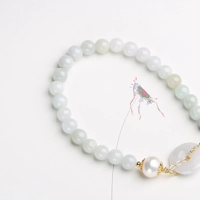 Natural emerald green jade and pearl bracelet with a geometric peace buckle clasp.