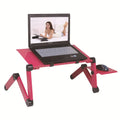 Red metal folding computer desk with cooling fans on a bed, holding a keyboard and mouse