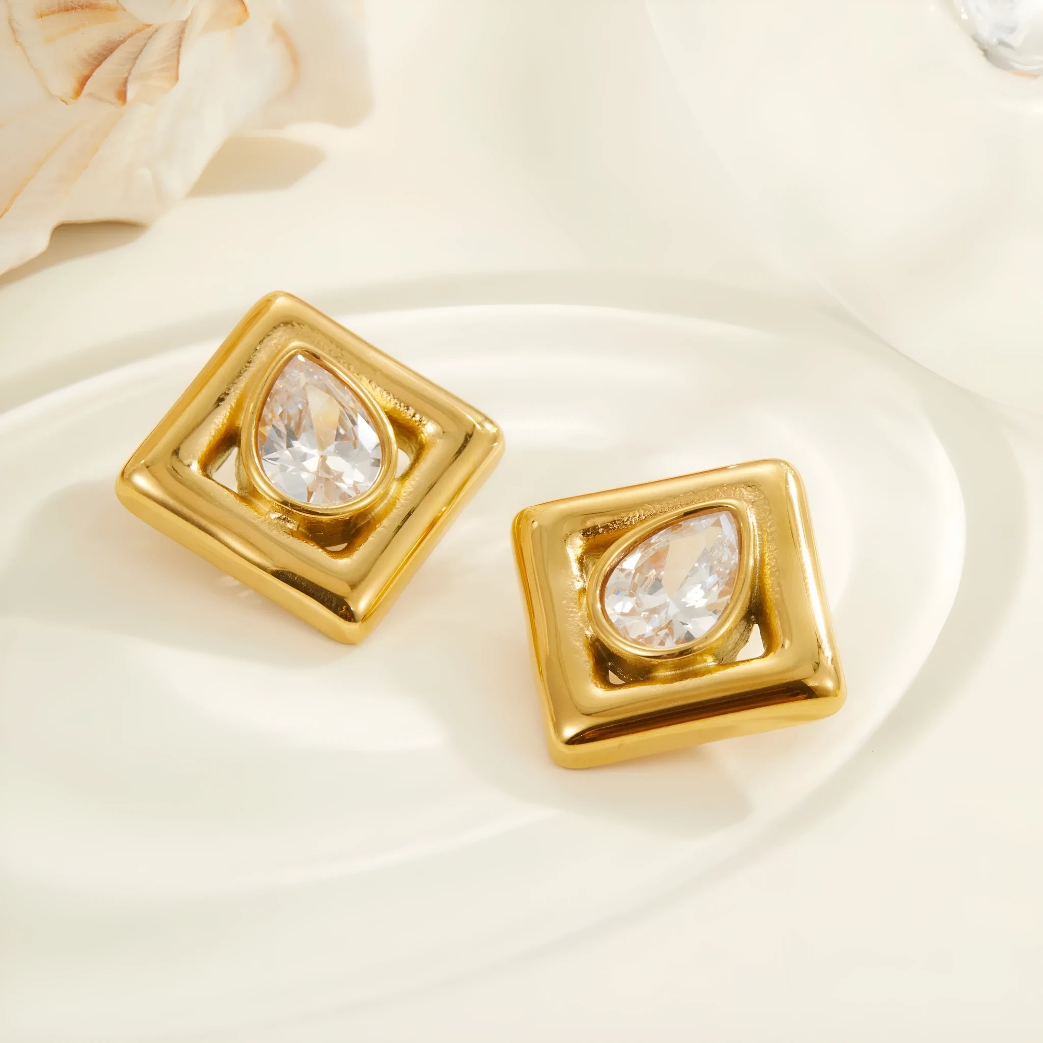 Gold geometric water drop shaped stud earrings with a central zircon stone inlay.