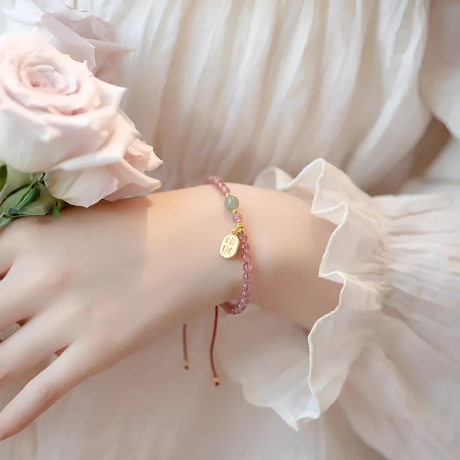 Hand-woven red rope bracelet with a strawberry quartz crystal charm on a wrist.