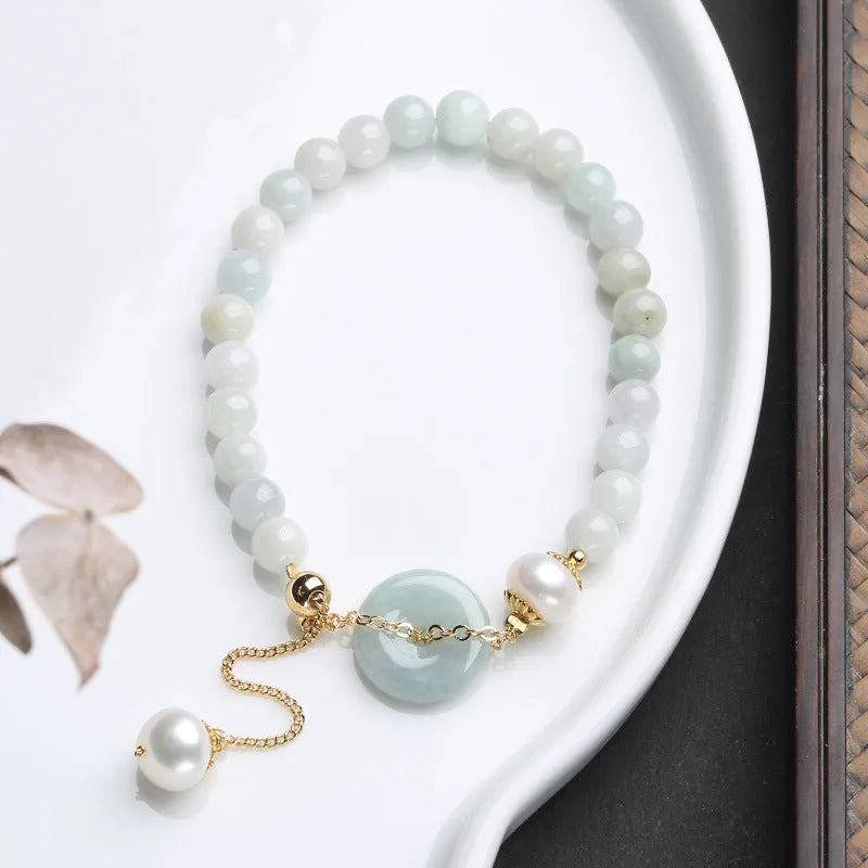 Natural emerald green jade and pearl bracelet with a geometric peace buckle clasp.