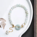 Natural emerald green jade and pearl bracelet with a geometric peace buckle clasp.