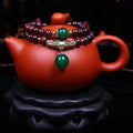 Natural deep red garnet bead bracelet with a golden toad charm, shown in 7mm size on a wrist.