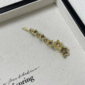 Gold-coloured alloy hair barrette with a side clip, rhinestones, a star, and a word decoration.