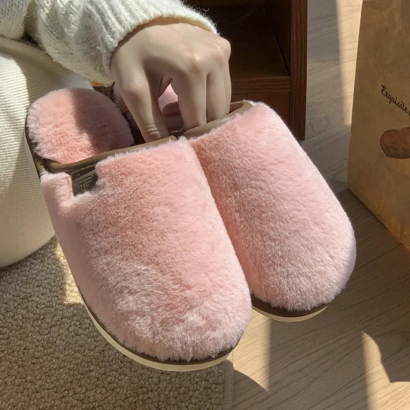 Pair of solid blue plush winter slippers with non-slip PVC sole on a wooden floor.