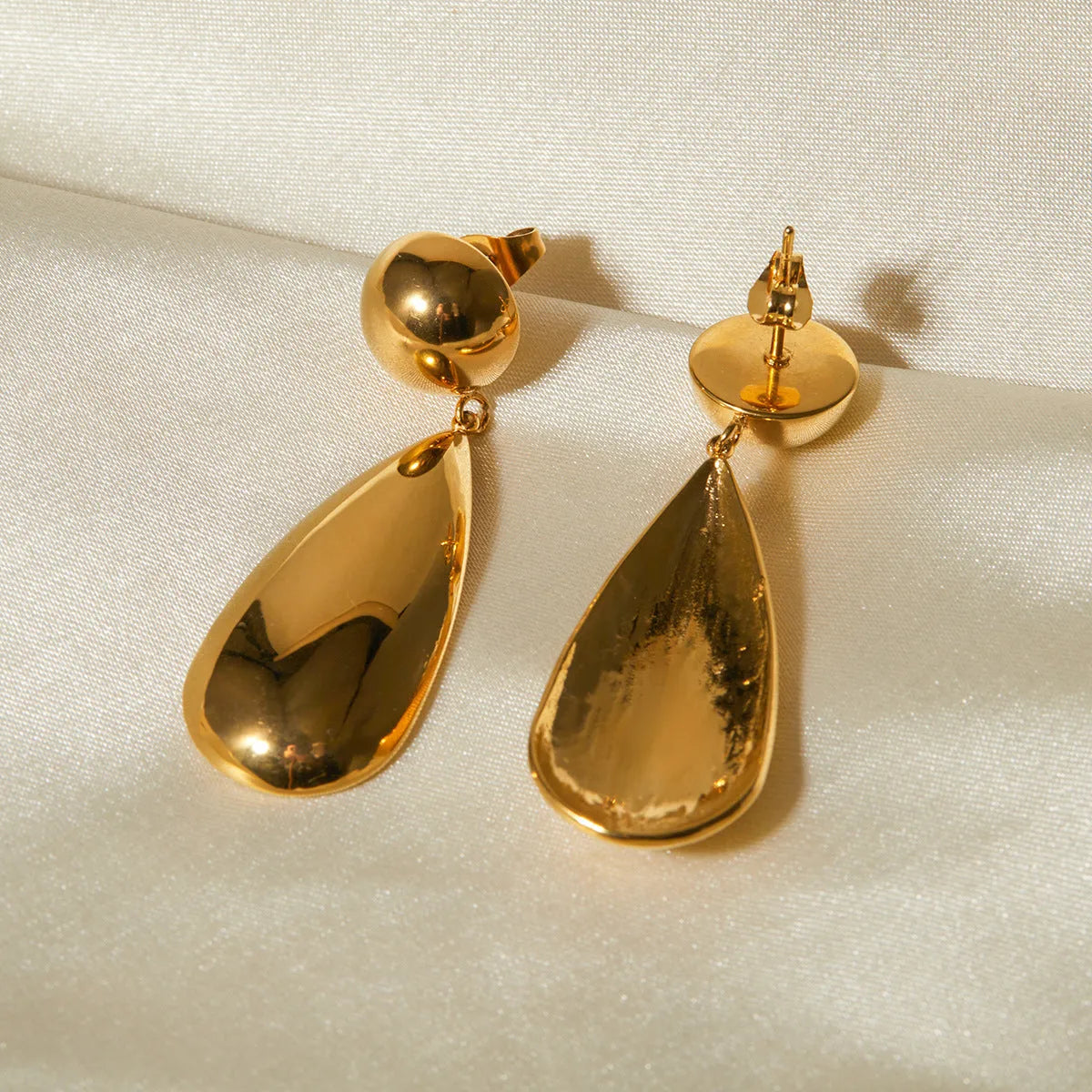 Gold electroplated stainless steel earrings with geometric hemisphere and water droplet pendant design