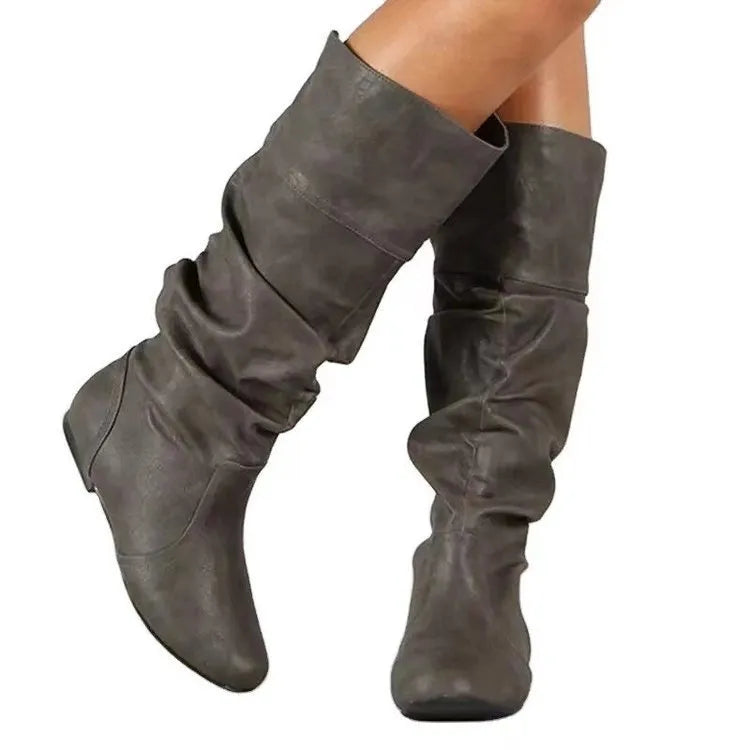 Women's black slip-on flat ankle boots with round toe and high cylinder shaft on a neutral background.