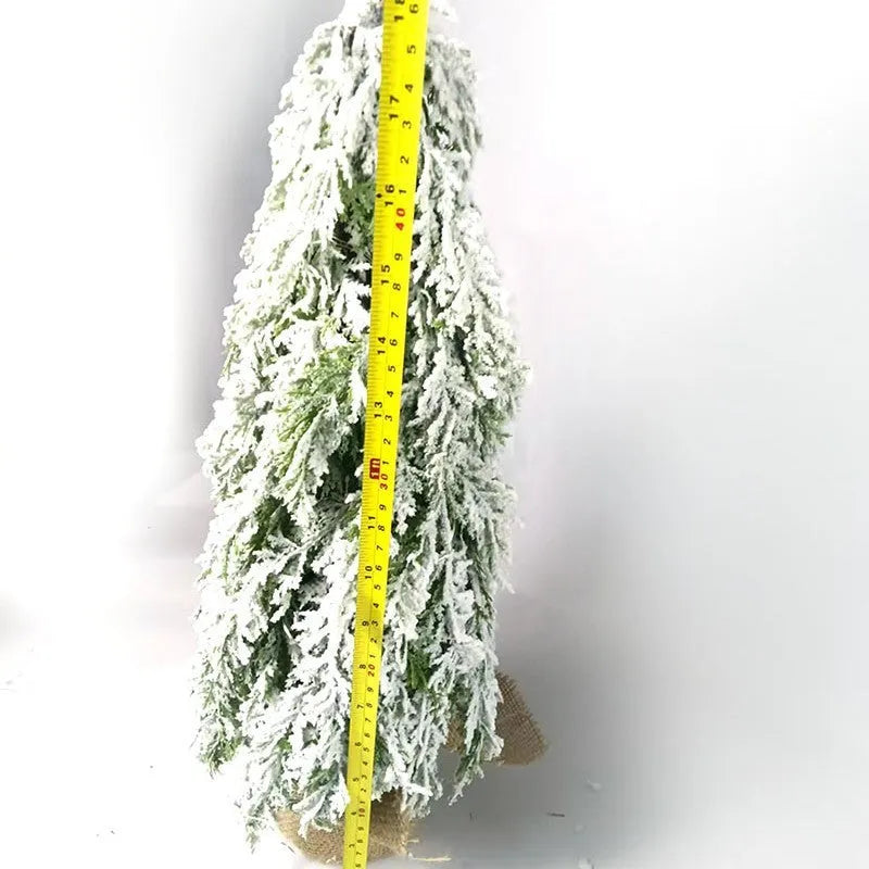 Small 24 inch artificial Christmas tree with lights and snow effect on a desktop