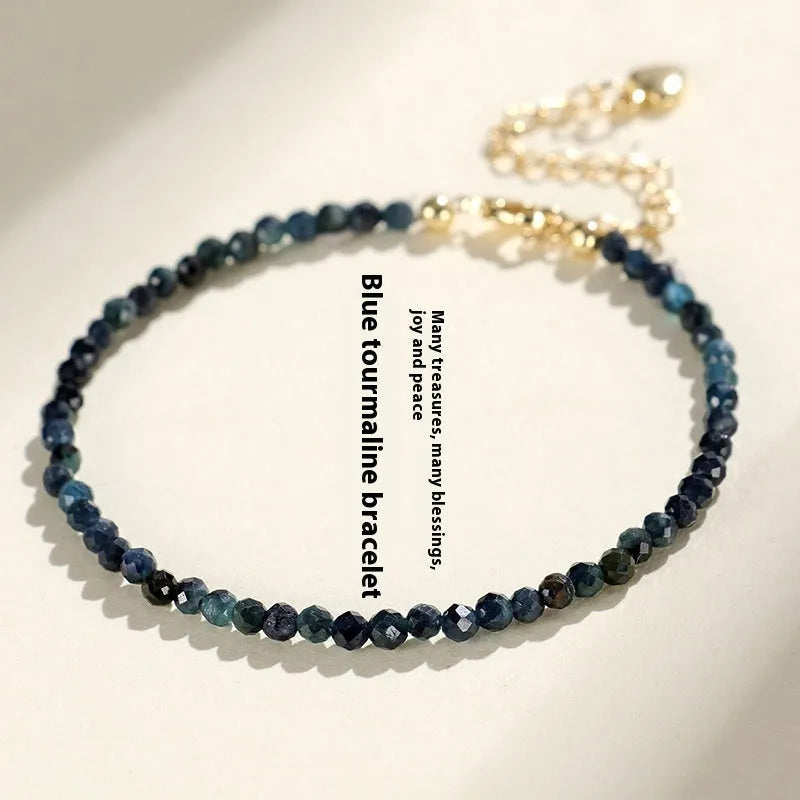 Close-up of a women's bracelet with small blue tourmaline beads and spacer beads on a wrist.