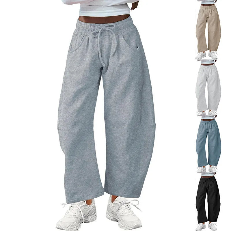 Woman wearing loose grey cropped sweatpants with drawstring waist and side pockets, street fashion style.