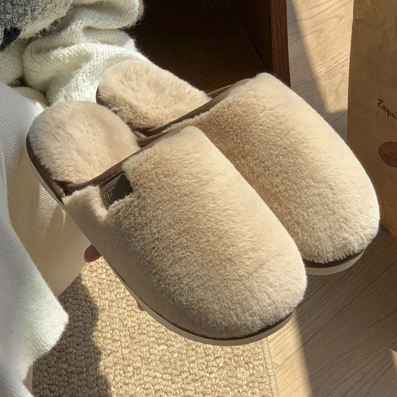 Pair of solid blue plush winter slippers with non-slip PVC sole on a wooden floor.