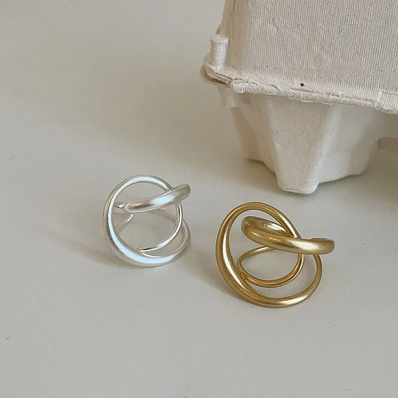 Geometric open ring for women with a three-dimensional interlaced design in matte metal.