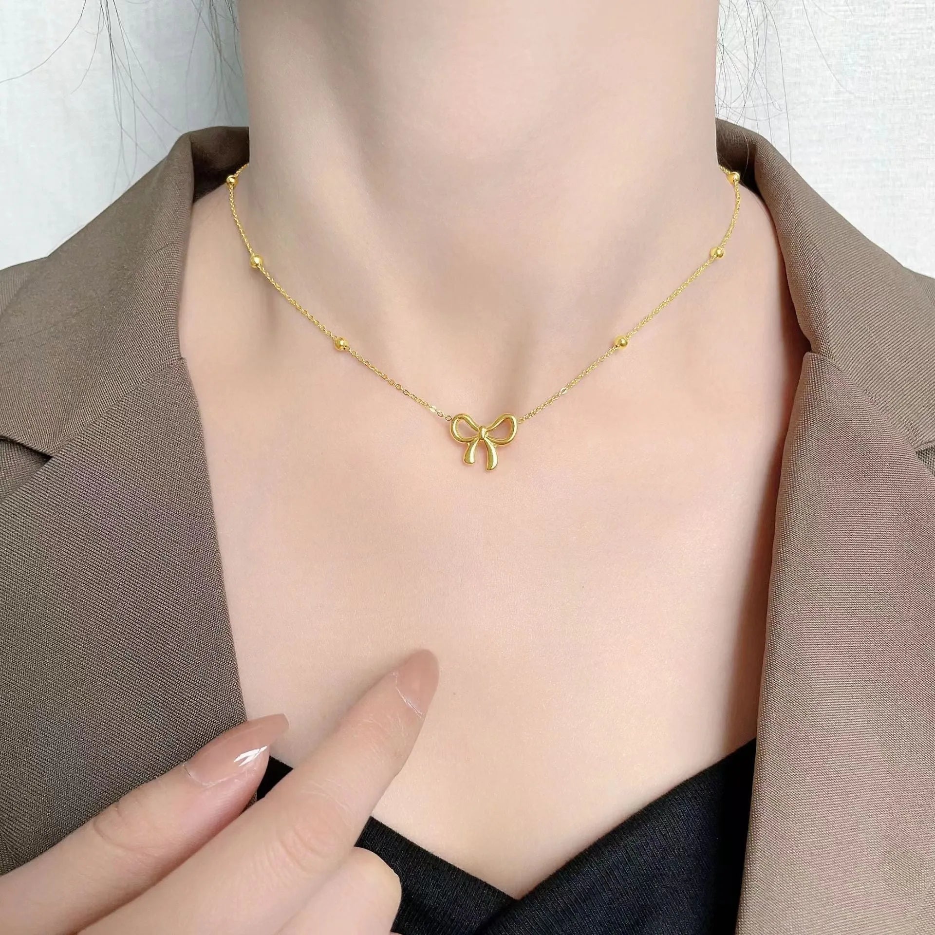 Gold electroplated bow pendant necklace with titanium steel cross chain, adjustable length
