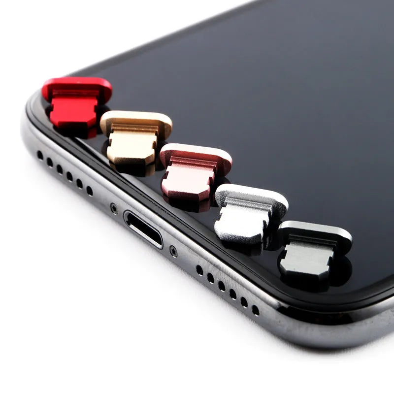Aluminium alloy iPhone charging port dust plug in metallic colours on a dark background.