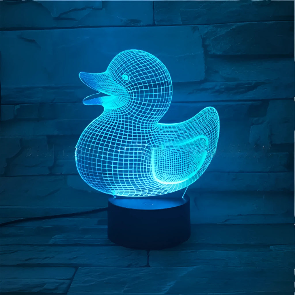 Little yellow duck 3D table night light showing seven colour options on a desk next to its black remote control.