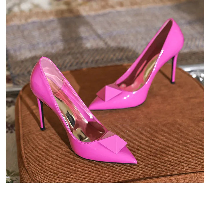 Pink women's pointed toe stiletto high heels with a buckle fastening on a patent leather upper.