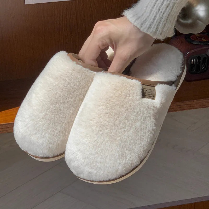 Pair of solid blue plush winter slippers with non-slip PVC sole on a wooden floor.