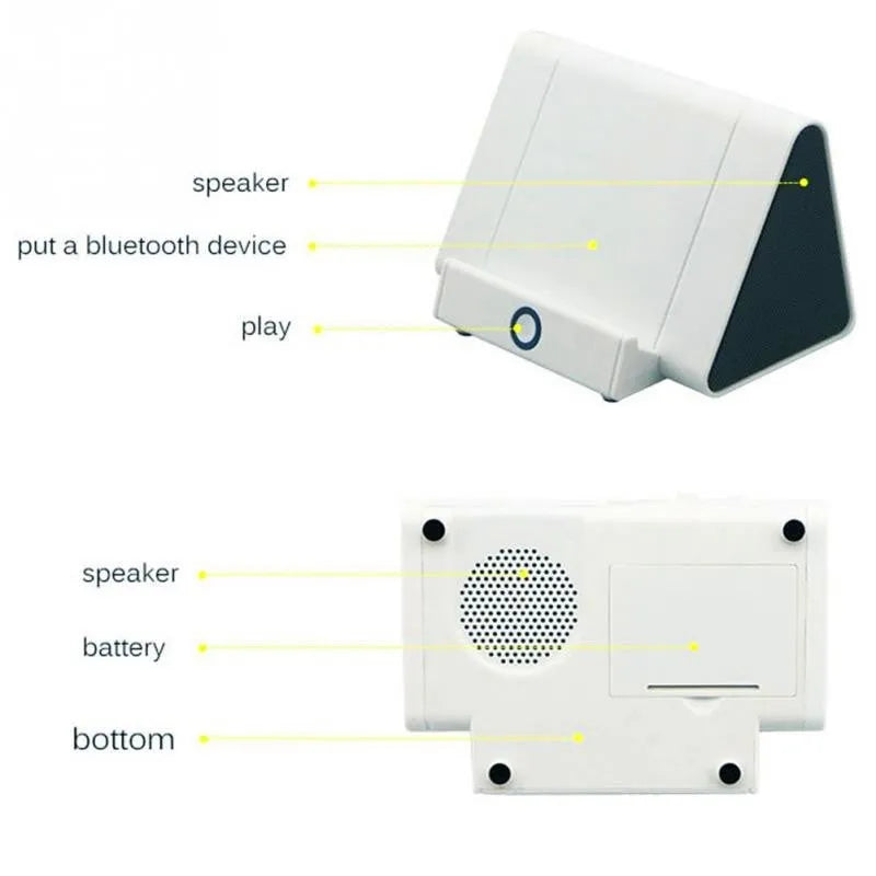 Small black or white wireless Bluetooth speaker with built-in charging cable on a desk next to a mobile phone