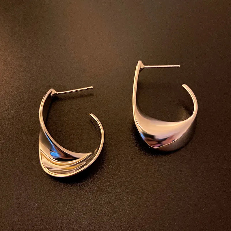 Gold and silver geometric twisted metal earrings with round design elements