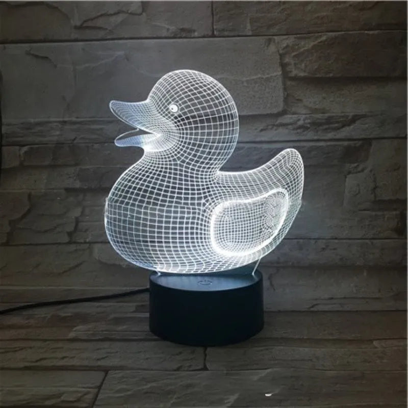 Little yellow duck 3D table night light showing seven colour options on a desk next to its black remote control.