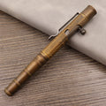 Solid brass bolt-action tactical pen with machine gun design on a dark surface.