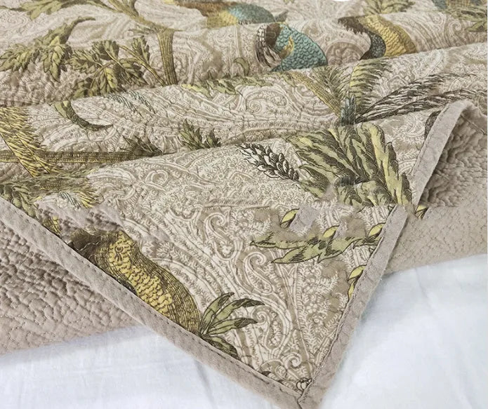 Blue American floral and bird pattern cotton bedspread quilted set of three pieces on a bed.